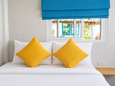 Double bed with yellow cushions and blue blinds in a beach bungalow