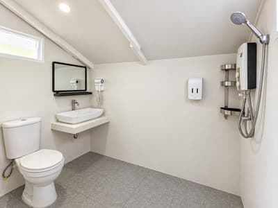 Beach house bathroom with a shower, washbasin, mirror, hair dryer and toilet