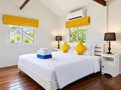 Double bed with yellow cushions in a bright beach house bedroom