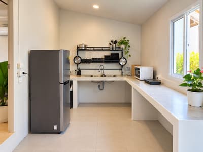 Beach house kitchen with a fridge, sink, microwave and cooking utensils