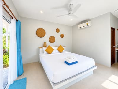Air-conditioned beach studio bedroom with a ceiling fan and large double bed