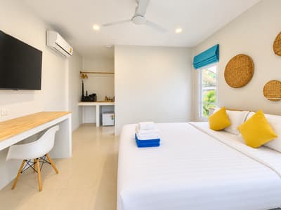 Beach studio desk, white chair and wall-mounted television beside the bed