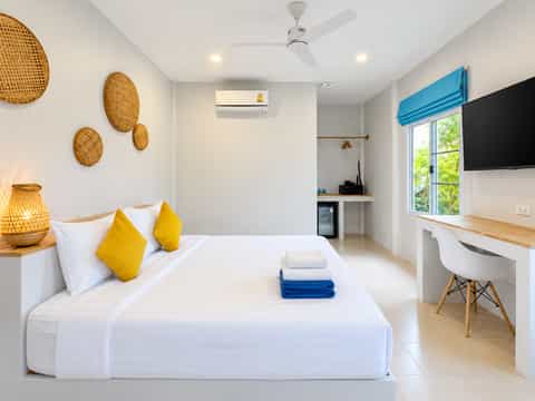 Beach studio bed with yellow cushions, woven wall decorations and blue blinds